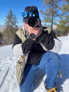 Jamie Harrell kneeling down behind a camera lens.