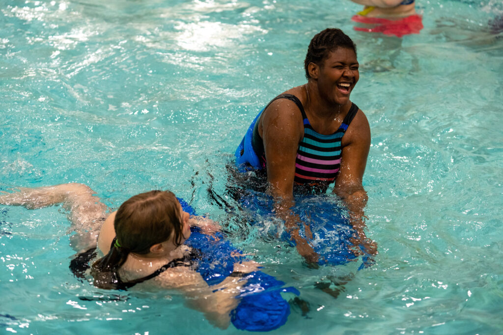 Athlete and swim guide laughing in the pool.